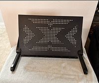 Front view of black perforated laptop stand on surface
