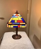 Front view of stained glass table lamp showing multicolour geometric shade and full base