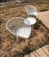 two white lattice-back patio chairs with matching round table