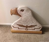 Front view of stone carved eagle head on wood base