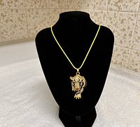 Front view of gold-tone rhinestone tiger pendant on yellow cord necklace displayed on black bust