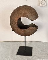 Front view of C-shaped copper currency on stand