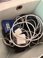 Top view of bin showing USB cables, Apple adapters, blue converter box, Timex clock