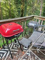 Red and grey charcoal grills on wheeled stands