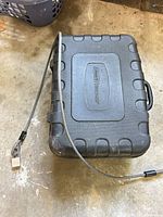 Closed hard case with braided security cable and padlock attached