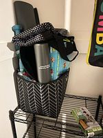 Bin containing yoga mat, water bottle, resistance bands packaging, storage bin