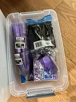 Purple disposable party pack with cups, utensils, napkins in plastic bin