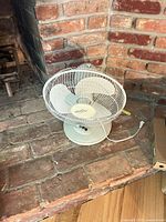White tabletop fan on brick hearth