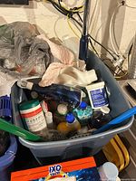 Bin containing assorted cleaning bottles, wipes, brush head, mop pad