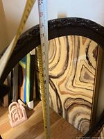 Oval mirror with measuring tape and canvases, pink bookends partly visible