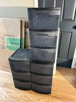 Two plastic drawer towers with cardboard boxes behind