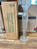 Frosted crystal bud vase standing beside box