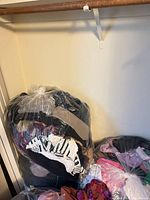 Three clear plastic bags stuffed with various women’s plus-size garments