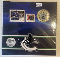 Front of display folder showing coin, two stamps and Canucks logo