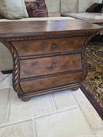 Front view showing three drawers, carved sides, overall finish