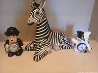 Group shot showing zebra figurine and two novelty clocks