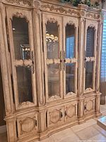 Full frontal view showing four glass doors, lower storage doors, carved details, finish