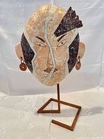 Full view of marble mosaic face sculpture on metal stand