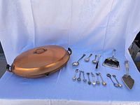 Copper chafing dish with lid and group of spoons and serving pieces