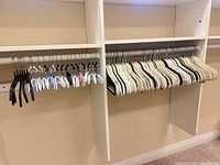 Overview of mixed hangers on closet rod showing quantity and variety