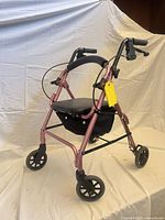 Full view of Nova pink 4-wheel rollator showing frame, seat, wheels, brakes, storage bag