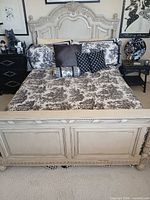 Full view of assembled bed showing carved headboard and bedding for scale