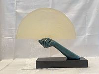 Lamp assembled showing glass fan shade held by teal hand on black base