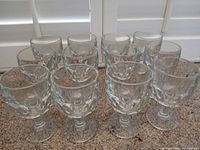 Front view of all 12 matching clear pressed glass wine goblets