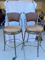 Front view of both metal swivel bar stools showing design and wear
