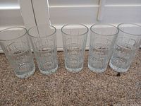 Five matching clear pressed-pattern glass tumblers aligned side by side