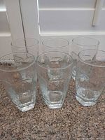 Six clear textured glass tumblers grouped on countertop