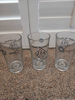 Three identical commemorative pint glasses upright on countertop
