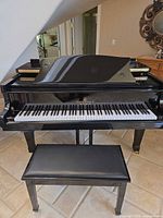 Front view of black polished Story & Clark grand piano with keyboard and bench