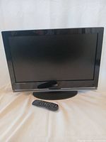 Front view of Vizio TV on stand with remote
