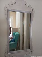 Front view of rectangular whitewashed wood mirror with ornate top and bottom detailing