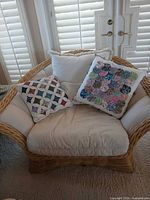 Front view of wicker rattan accent chair with cushions and two decorative pillows