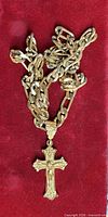 Crucifix pendant attached to gold plated chain on red background