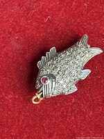 close-up of fish pendant front, showing pavé diamonds and ruby eye