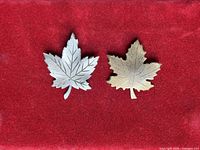 Both maple leaf brooches front view on red background