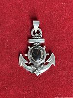 Front view shows anchor pendant, black cabochon stone, rope and wheel details