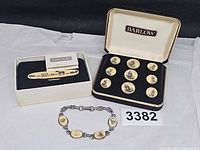 Full lot showing tie clip in box, cufflink/button set in case, bracelet, lot tag