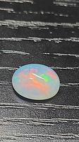 Oval crystal opal cabochon showing red and green play of colour