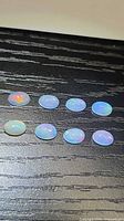 Eight oval opals on dark surface, showing play-of-color