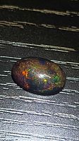 Top view of oval cabochon opal displaying multicolored play-of-color