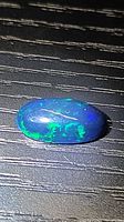 Top view of oval black opal showing blue and green flashes