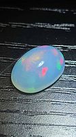 Top view of oval jelly opal showing multicolour flash