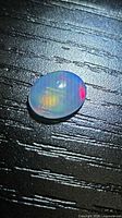 Oval cabochon opal showing color play on dark surface
