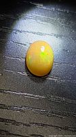 Front view of oval Ethiopian opal showing caramel body colour and play-of-colour