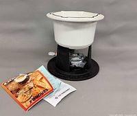 overall view of fondue pot on stand with booklet and paperwork