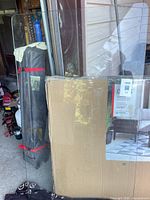 Full view of clear glass desktop leaning against wall, cardboard box beside for scale